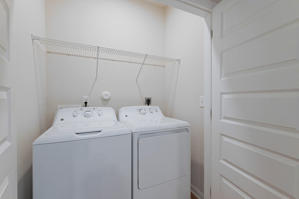 Two white washing machines in a small laundry room.