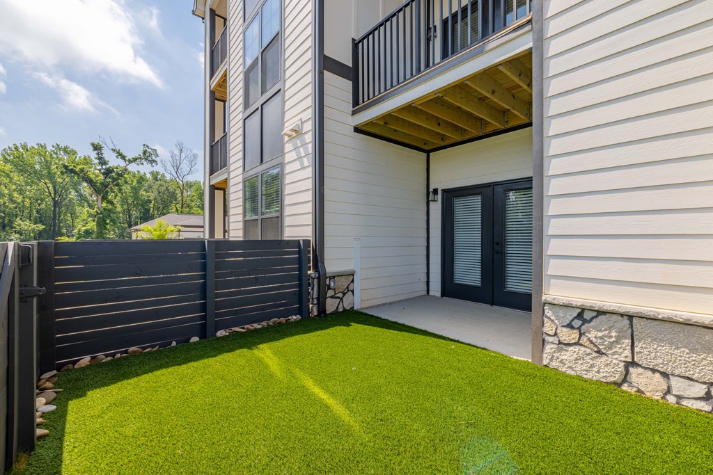 A small backyard with a wooden deck and a black fence.