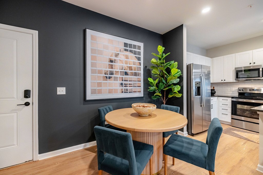 A kitchen with a table and chairs and a fridge.