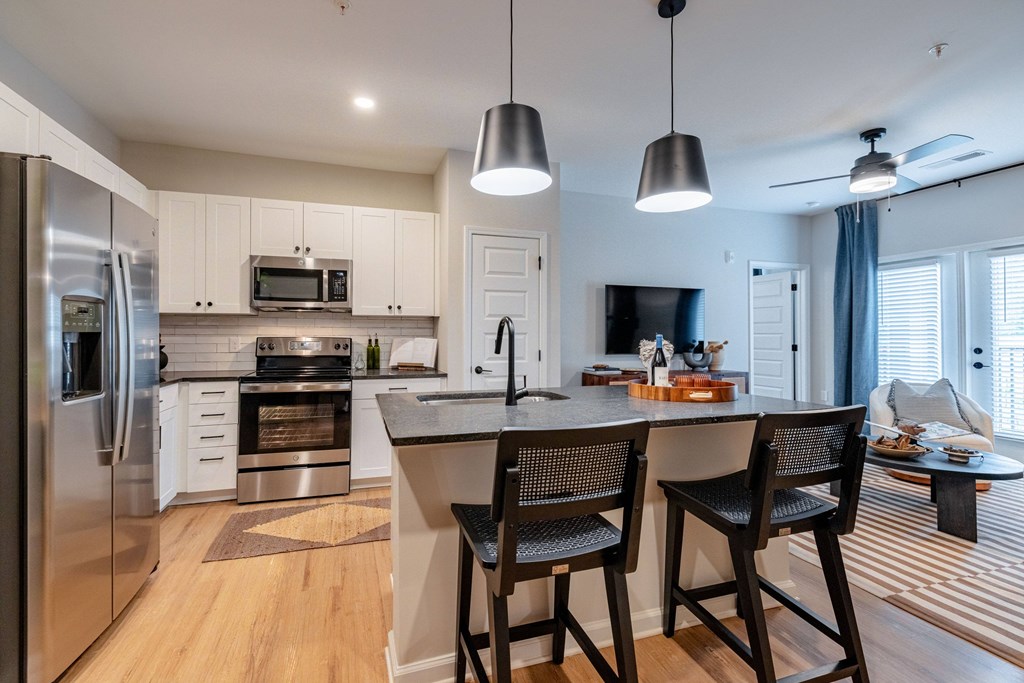 A modern kitchen with a refrigerator, microwave, oven, and sink.