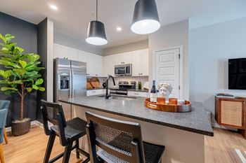 A modern kitchen with a dark wood floor and white walls.