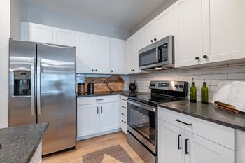 A modern kitchen with a stainless steel refrigerator and a microwave above the stove.