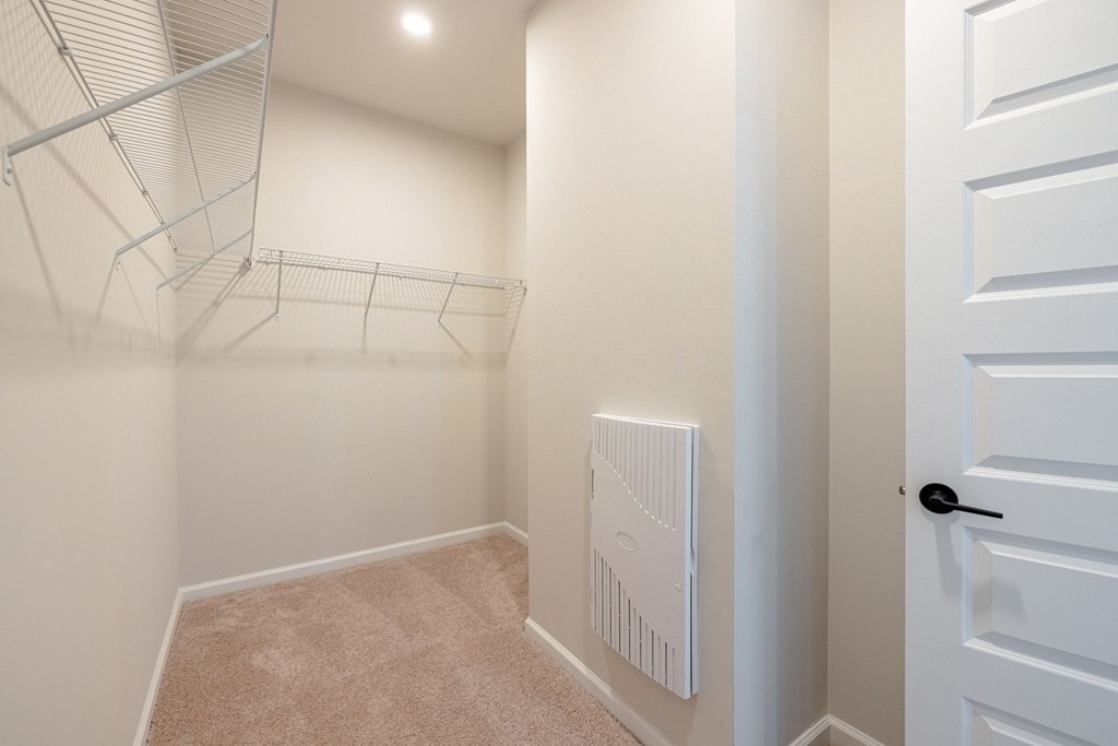 A white closet with a white door and a white radiator on the wall.