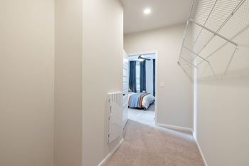 A room with a carpeted floor and a bed with a blue and orange blanket.