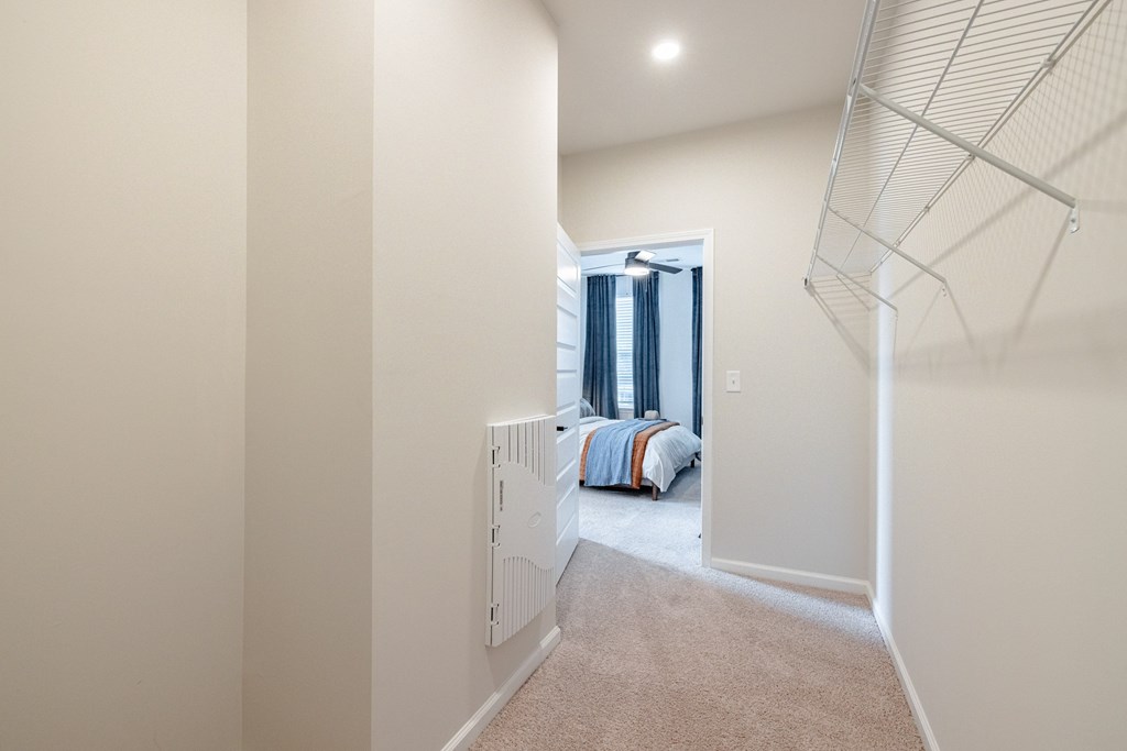 A room with a carpeted floor and a bed with a blue and orange blanket.