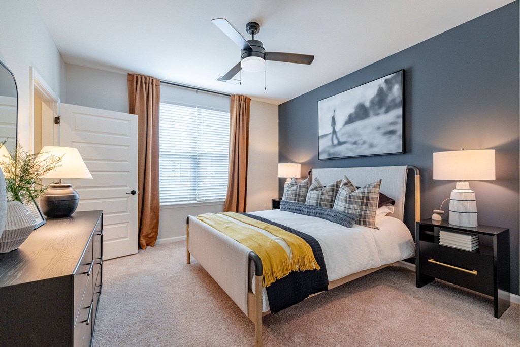 A bedroom with a bed, nightstands, and a ceiling fan.