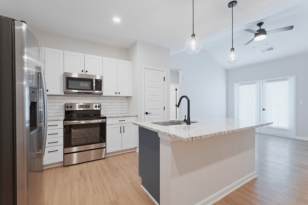 A modern kitchen with stainless steel appliances and a marble countertop.
