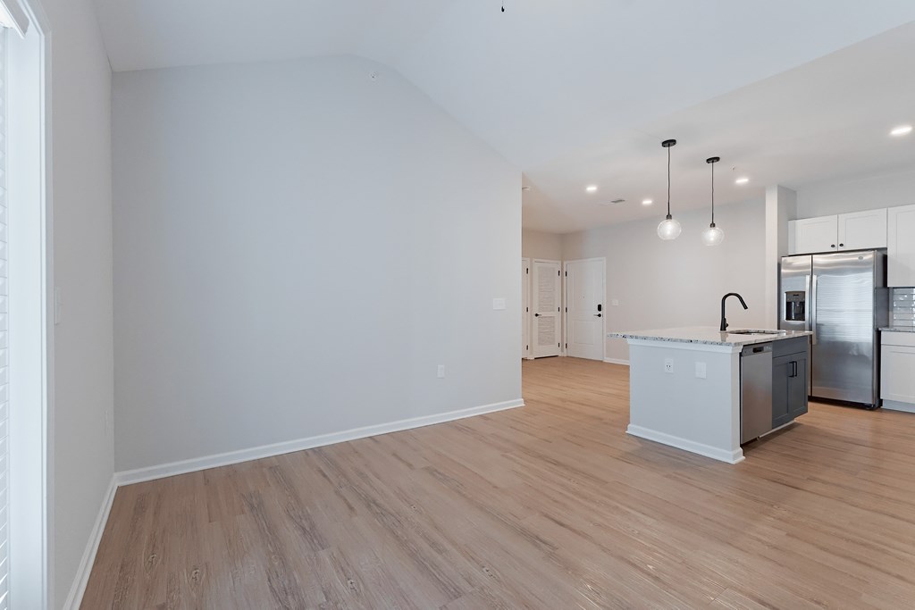 A kitchen with white walls and wooden floors.