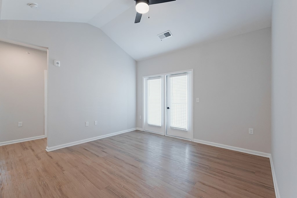 A room with a ceiling fan and sliding glass doors.