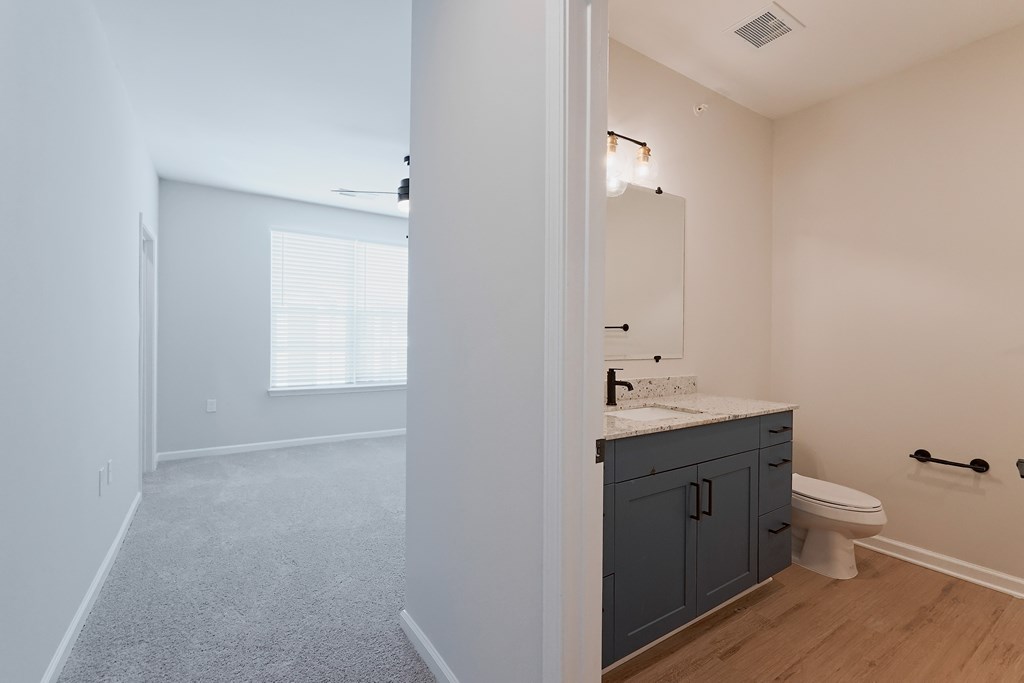 A bathroom with a toilet, sink, and a window.