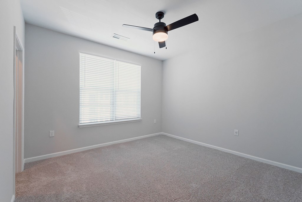 A room with a ceiling fan and a window with blinds.