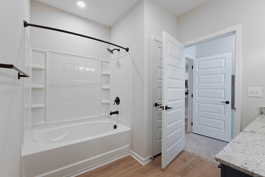 A white bathroom with a tub and a door.