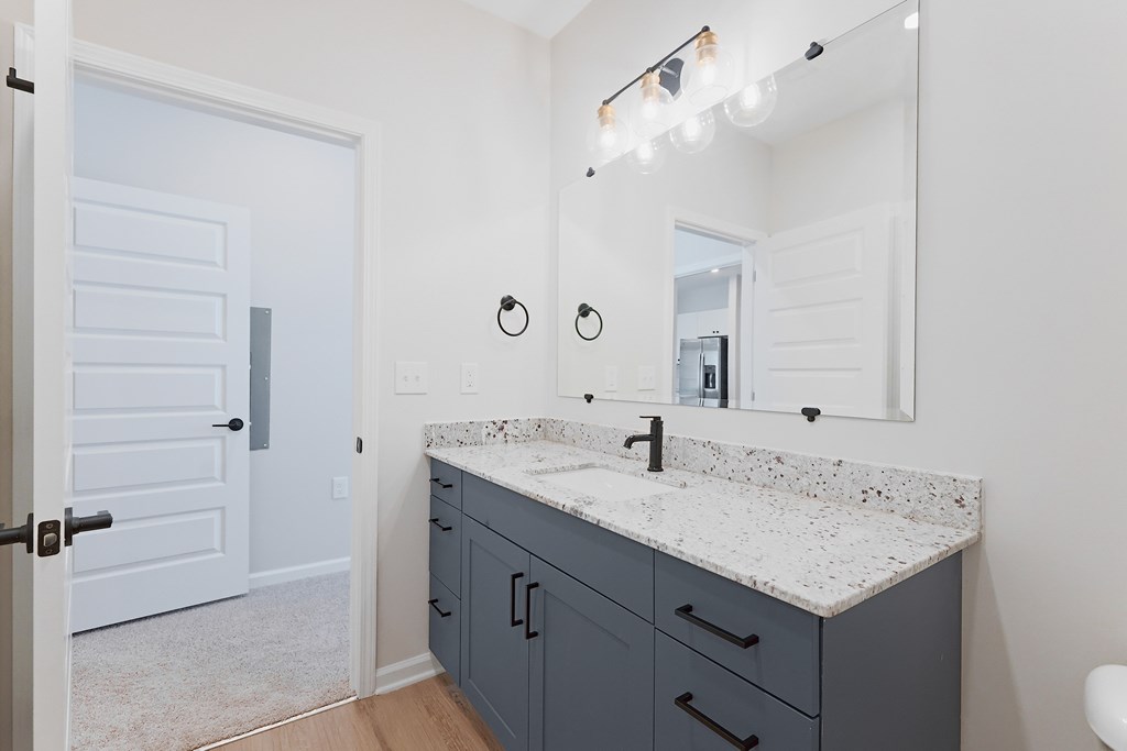 A bathroom with a sink, mirror, and lighting fixture.