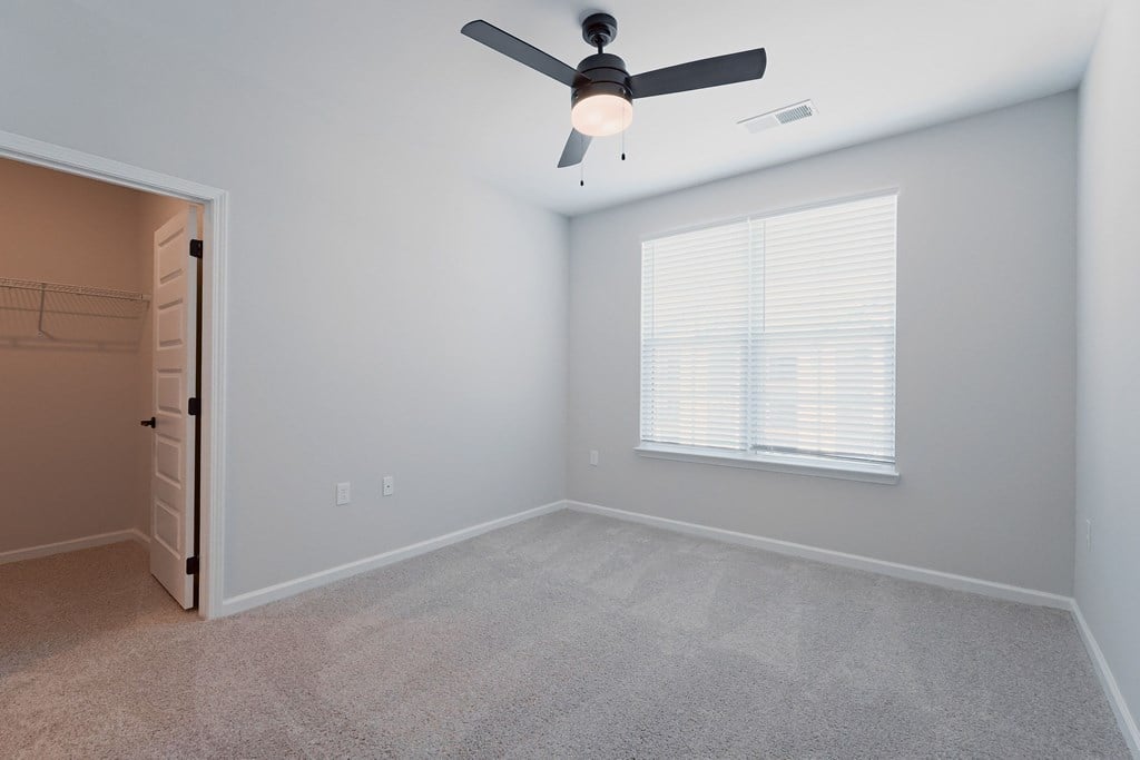 A room with a ceiling fan and a window with blinds.