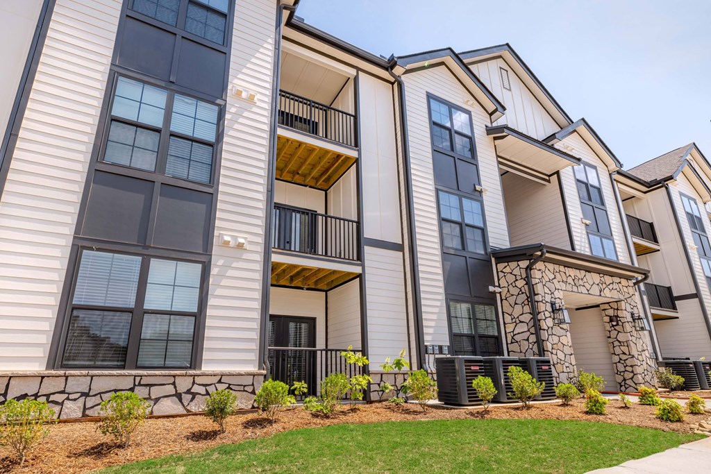 A modern apartment building with a balcony and a stone pillar.