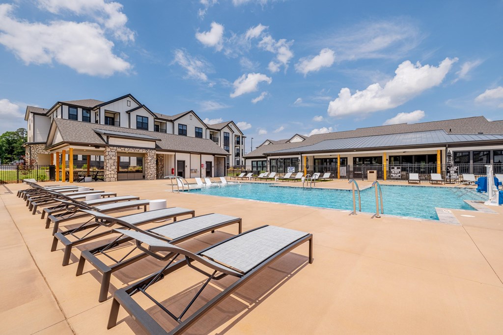 A poolside area with sun loungers and a building in the background.