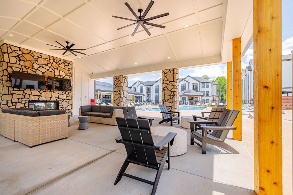 A patio with a black chair and a stone wall.
