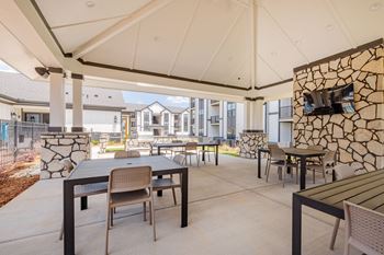 A patio with tables and chairs under a white canopy.