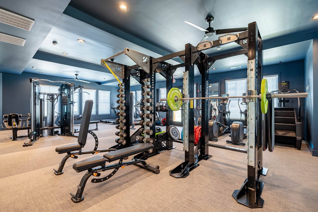 A gym with a variety of equipment including weight machines and a bench.