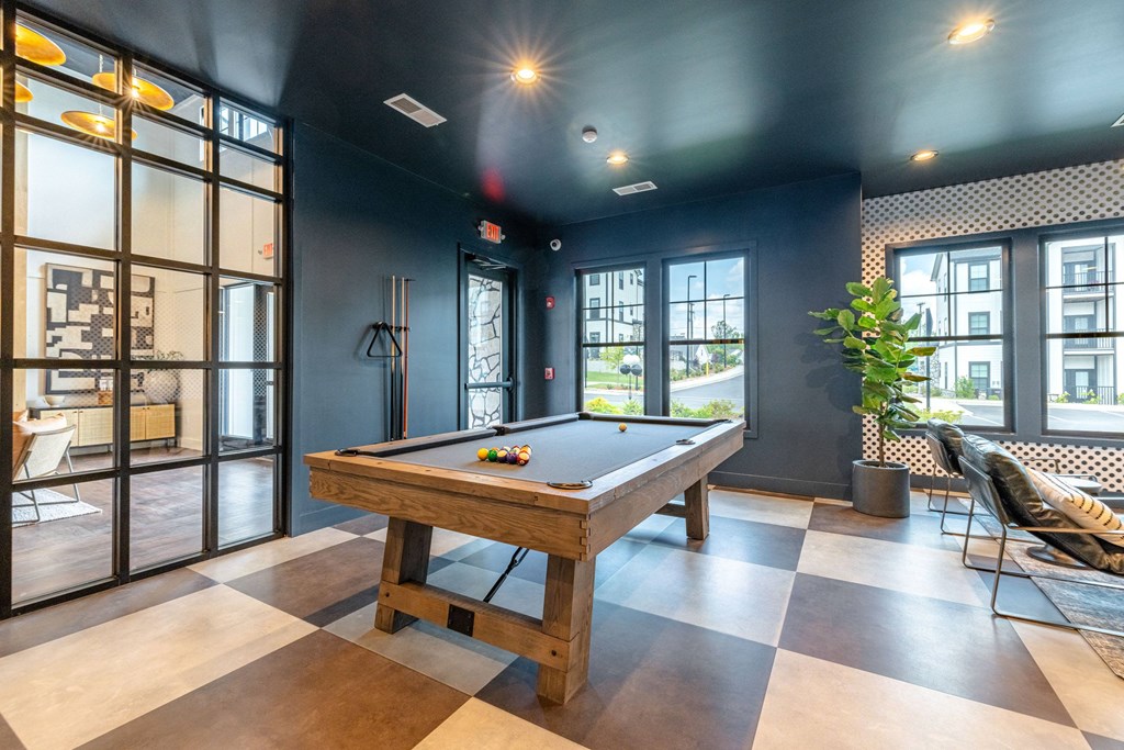 A pool table is in the middle of a room with a black ceiling and a checkered floor.