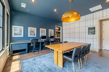 A room with a blue carpet and a wooden table with chairs.