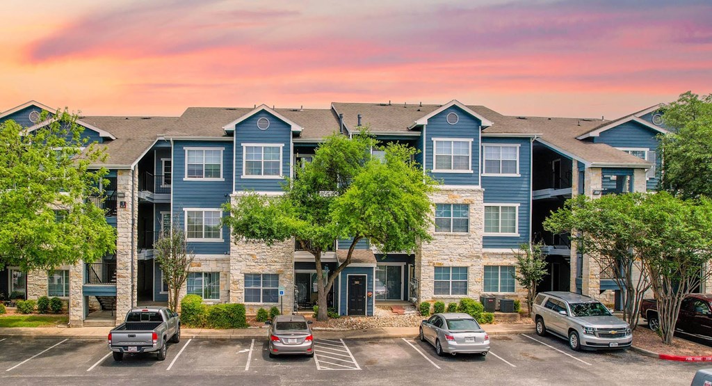 an apartment building with cars parked in a parking lot