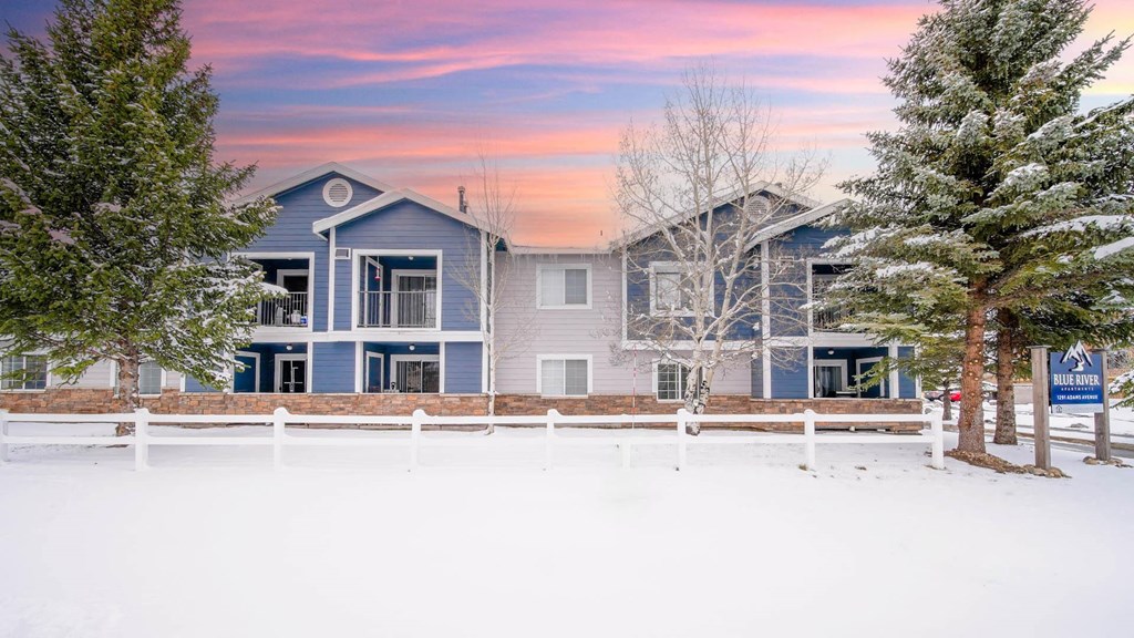 a snow covered yard in front of blue and white houses