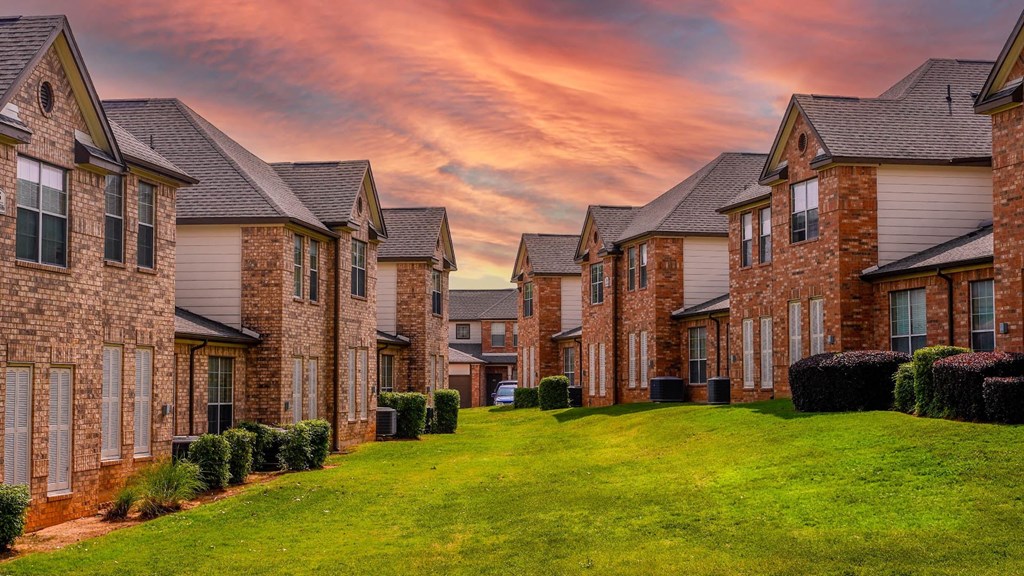 a row of brick houses on a green lawn