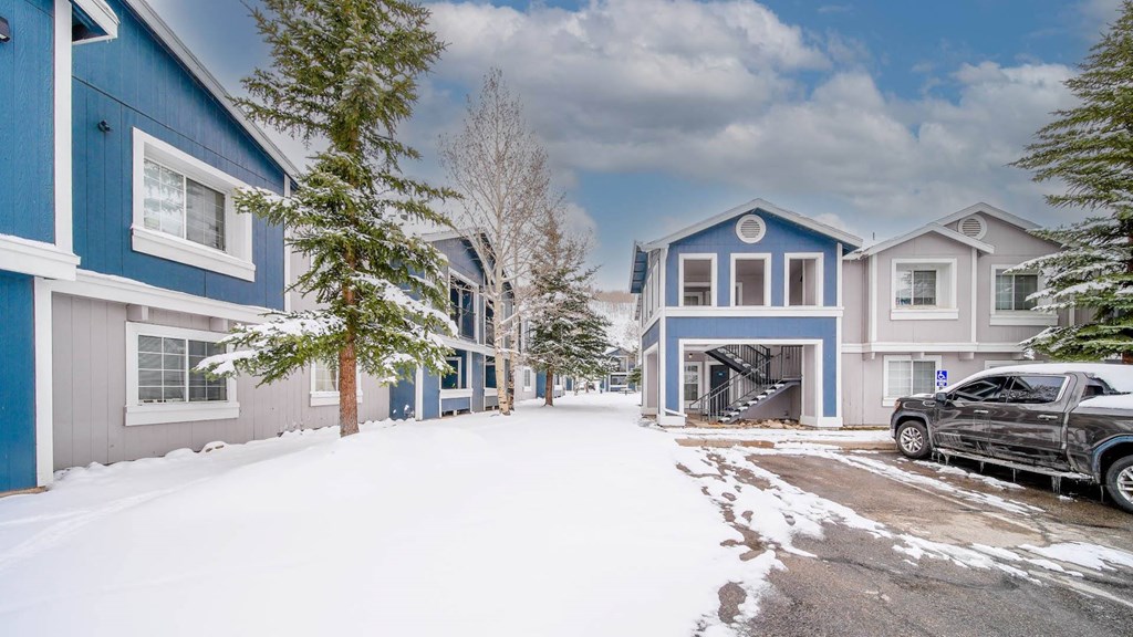 a car parked in front of some blue houses covered in snow