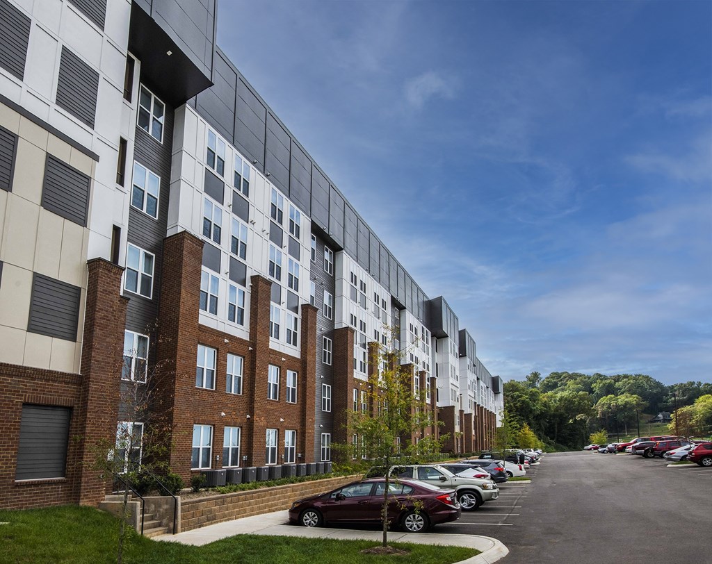 A modern apartment building with a parking lot in front.