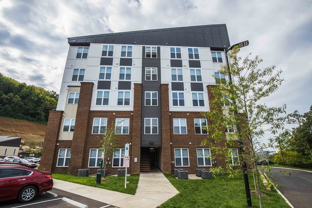 A modern apartment building with a red car parked in front.