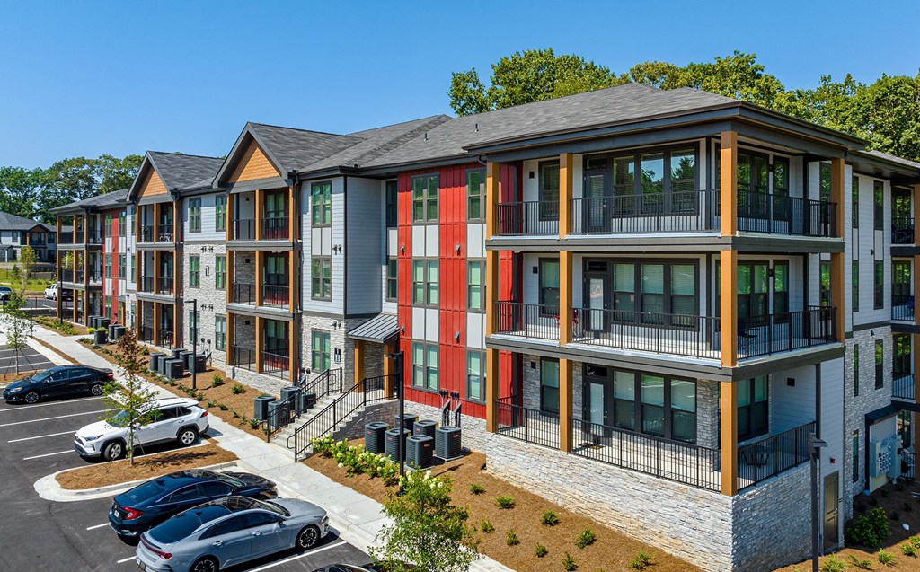 a row of apartment buildings with cars parked in a parking lot