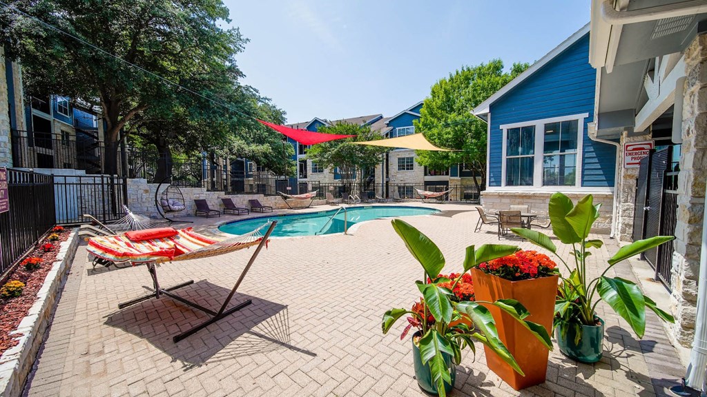 a swimming pool with patio furniture and umbrellas