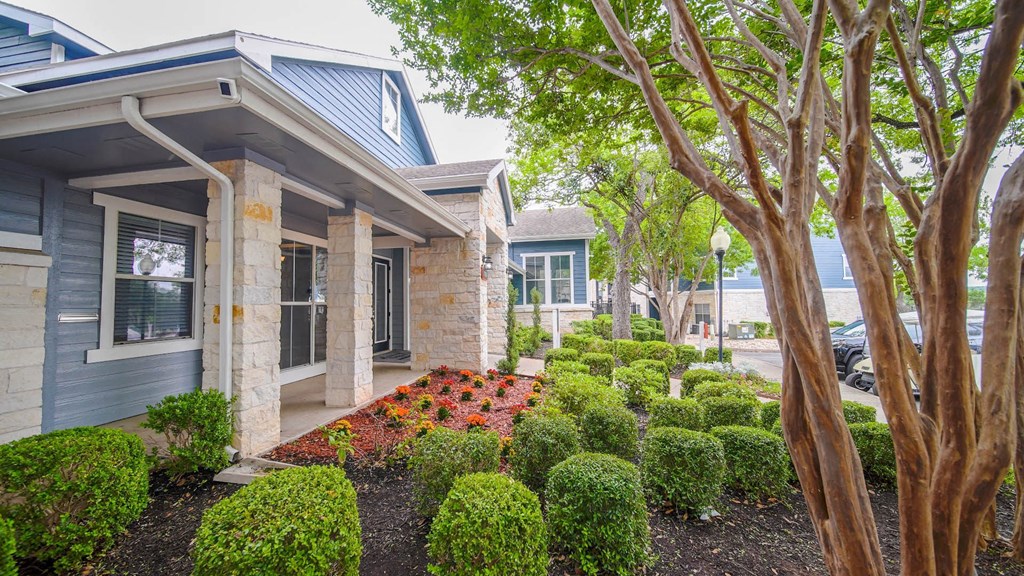 the front yard of a house with a garden and trees