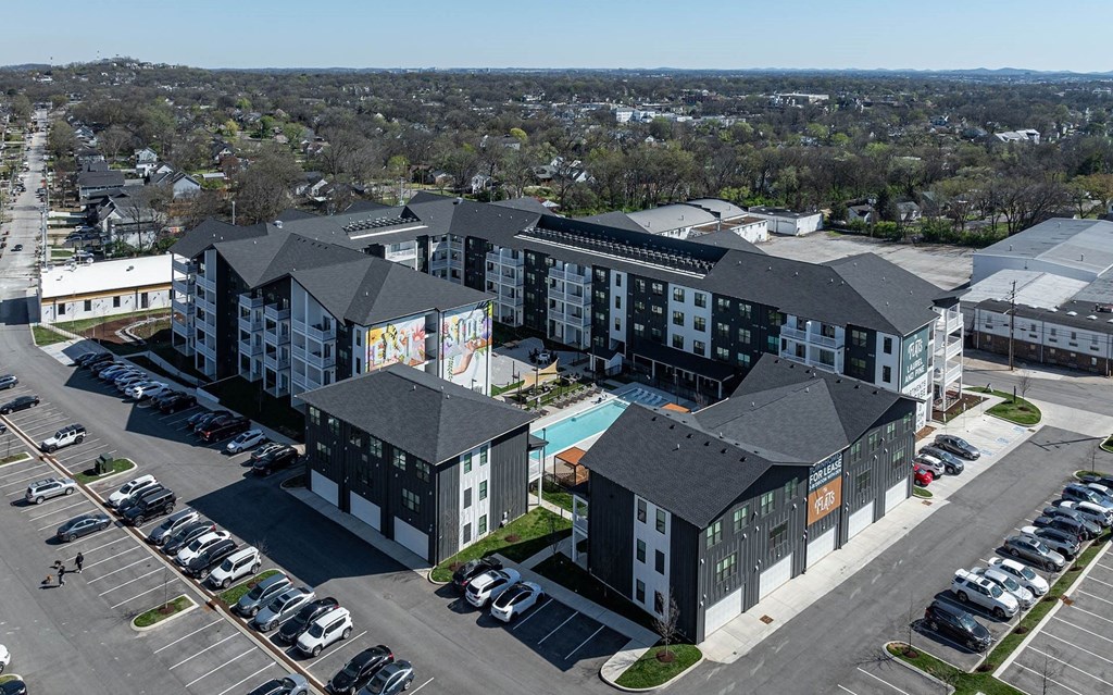an aerial view of an apartment complex with a swimming pool and parking lot