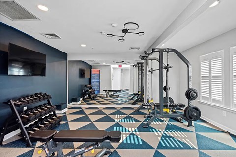 A gym with a variety of equipment including weights and benches.