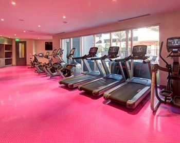 a row of cardio equipment in a gym with a pink floor