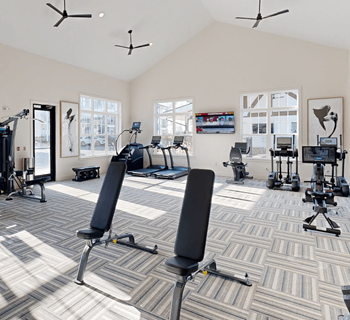 a workout room with weights and chairs in a large room with windows