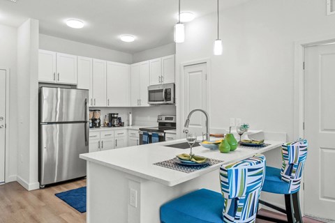 A kitchen with a white counter and blue chairs.