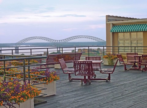 A wooden deck with chairs and a railing overlooking a body of water.