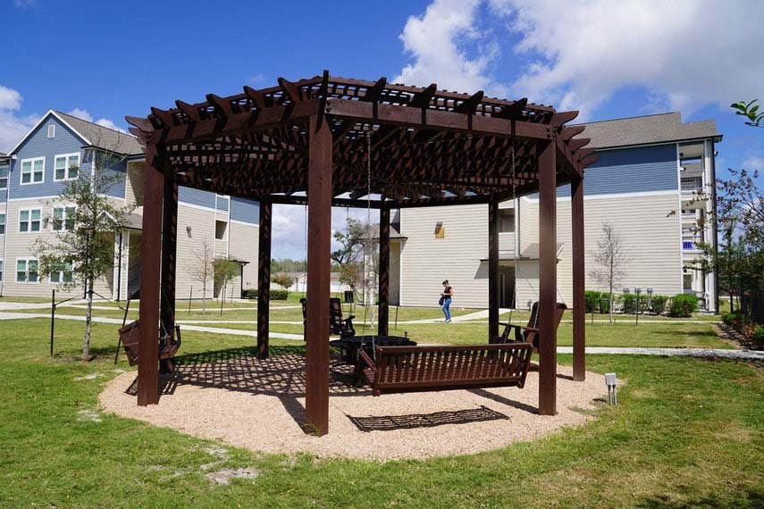 a bench under a wooden pavilion in a park