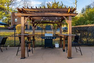 a pergola with two tables and a grill - Photo Gallery