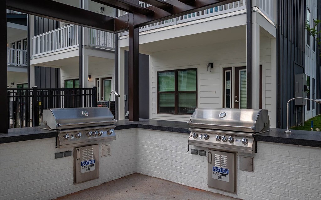 two stainless steel barbecue grills in front of a building