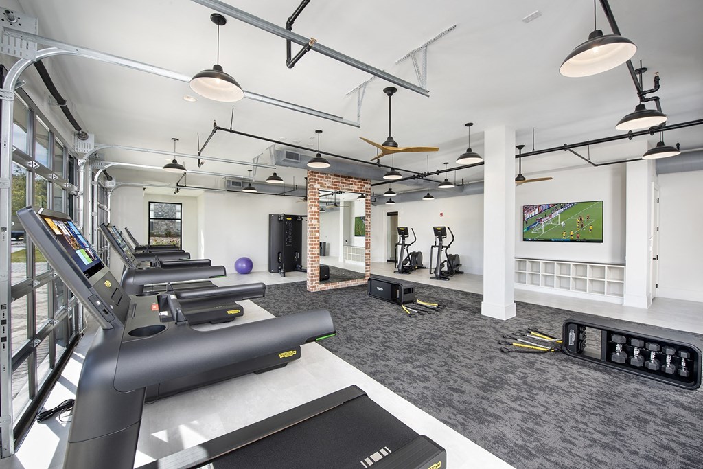 a gym with treadmills and other exercise equipment in a room with a tv