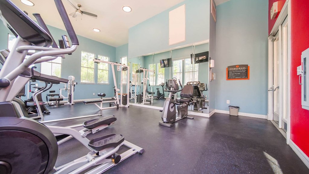 a gym with cardio machines and weights on the floor