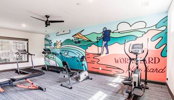 a workout room with a mural on the wall and exercise equipment