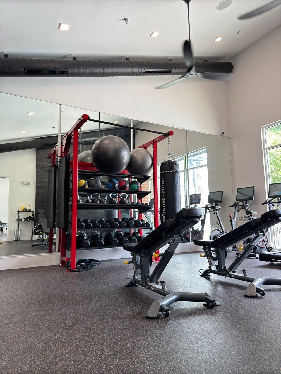 A gym with a variety of equipment including a weight rack and a bench.