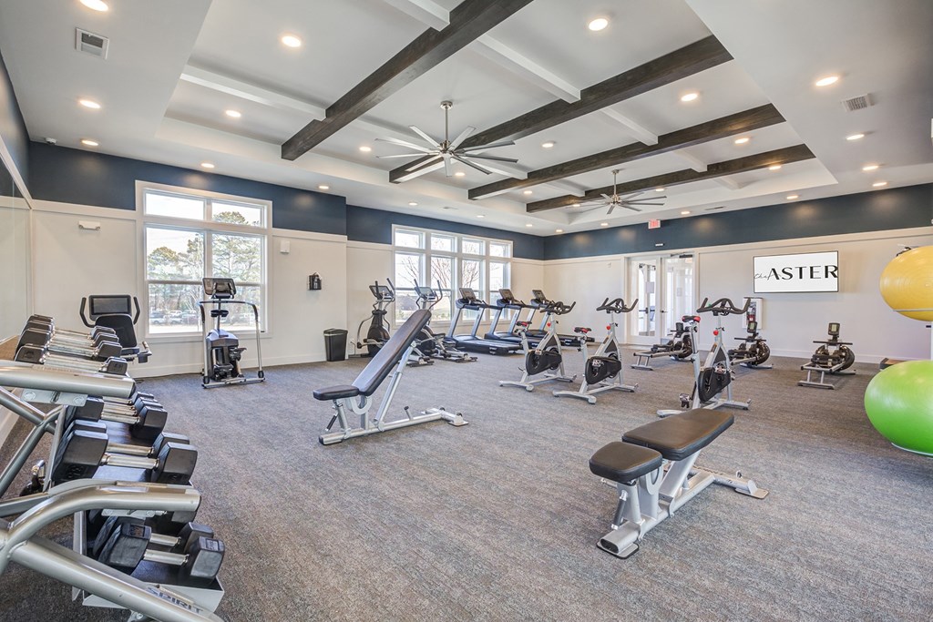 a gym with treadmills and other exercise equipment in a building with windows