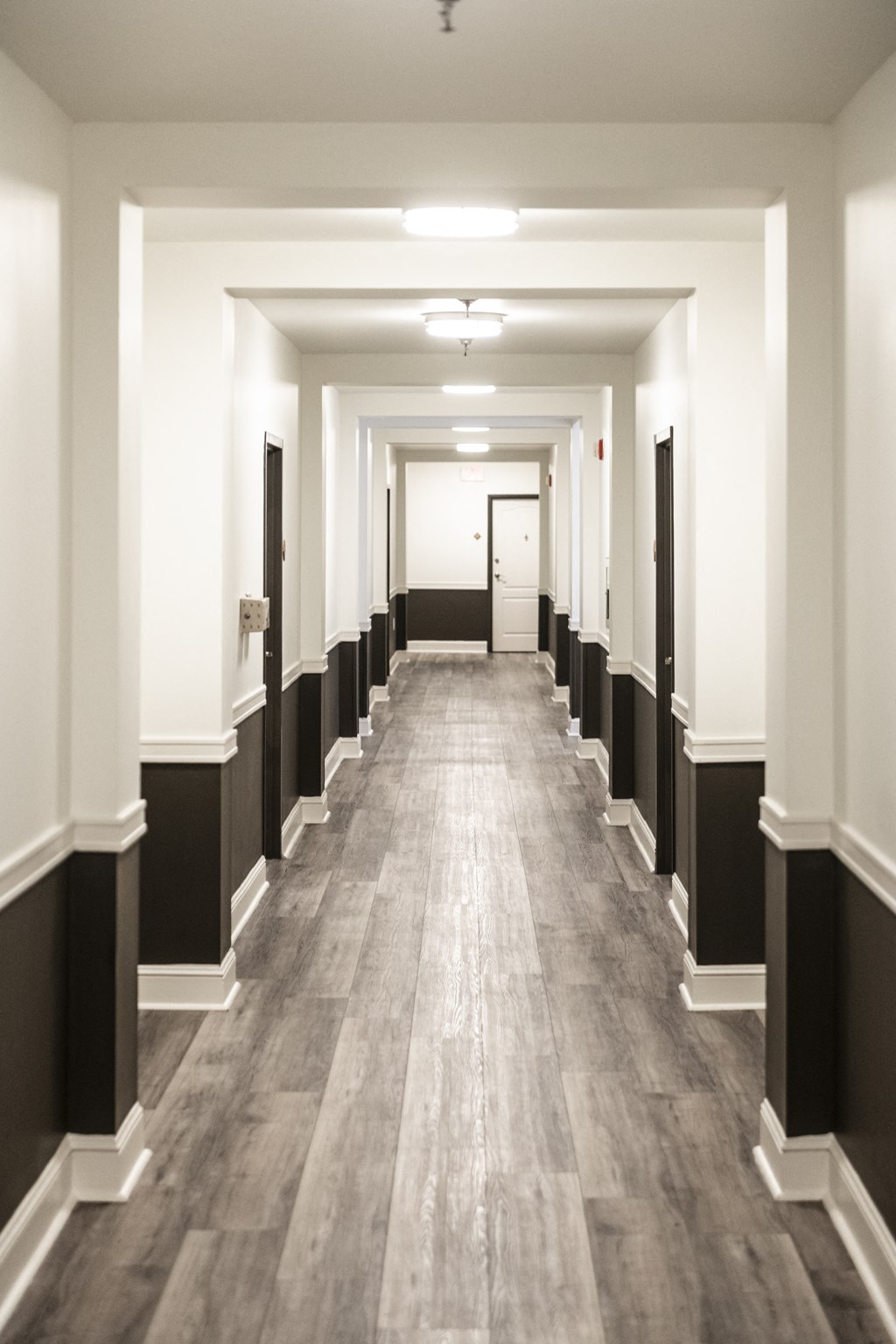 a corridor in a building with wood floors and black and white pillars