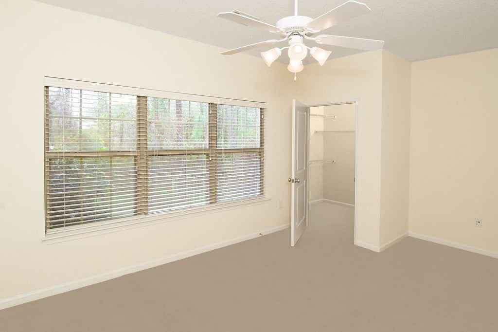an empty room with a large window and a ceiling fan